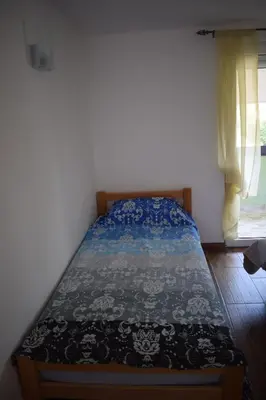 a bedroom with a bed with a blue and white comforter at Apartmani Gočki San in Biserske Kuće