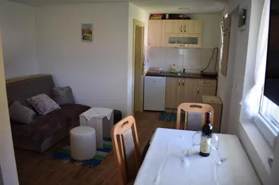 a small living room with a table and a kitchen at Apartmani Gočki San in Biserske Kuće
