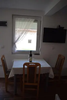 a dining room table with a window and a table and chairs at Apartmani Gočki San in Biserske Kuće