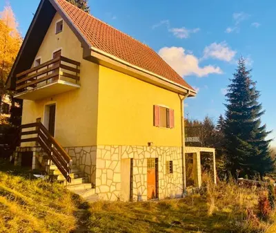 a small yellow house with stairs and a tree at Petra in Kopaonik