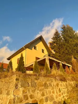 a yellow house on top of a stone wall at Petra in Kopaonik