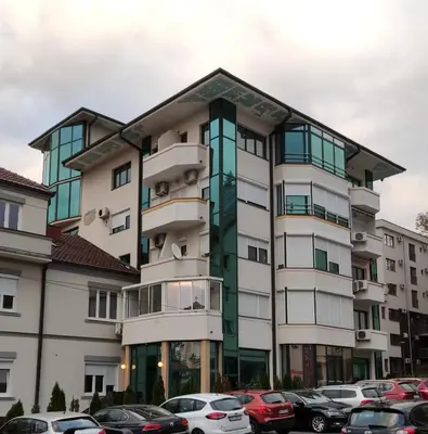 a building with cars parked in a parking lot at Apartman Vivaldi - CENTAR in Vrnjačka Banja