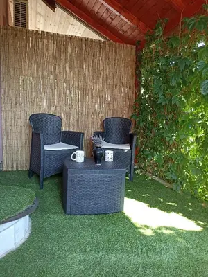 a patio with two chairs and a table on the grass at MonteCasa in Vrnjačka Banja