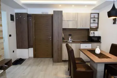 a kitchen with wooden cabinets and a table with chairs at Apartman Leki in Kopaonik