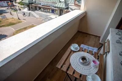 a balcony with a table and chairs and a view of a city at Promenada Grujić in Vrnjačka Banja