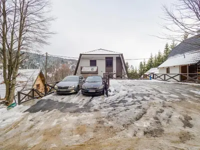 two cars parked in front of a house in the snow at Apartman Dve Skije, Apartmani Šišarka in Kopaonik