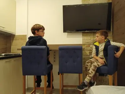 two boys sitting in chairs in front of a tv at Milmari N Lux 52 in Kopaonik