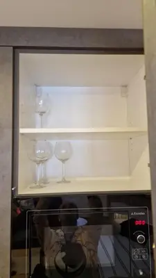 a shelf with wine glasses on top of a microwave at Xenia Apartment in Kopaonik