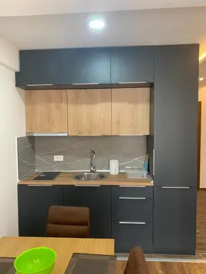 a kitchen with black cabinets and a sink and a table at President Kop A 735 in Kopaonik