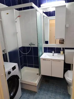 a bathroom with a shower sink and a washing machine at City Center Studio in Niš