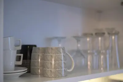 a coffee cup sitting on a shelf with other glasses at Tanis Apartments in Niš