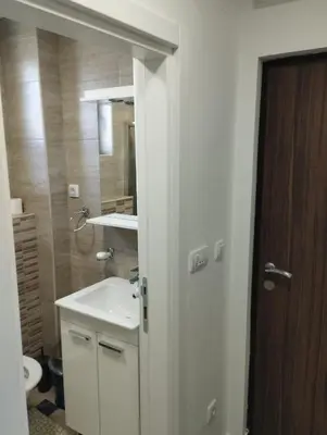 a bathroom with a sink and a toilet and a mirror at Apartman Iznad Oblaka in Kopaonik