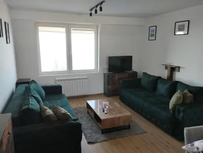 a living room with two green couches and a coffee table at Apartman Iznad Oblaka in Kopaonik