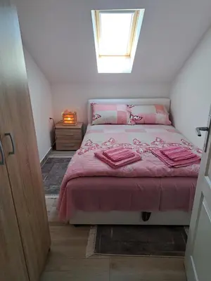 a bedroom with a bed with pink sheets and a window at Relja in Soko Banja