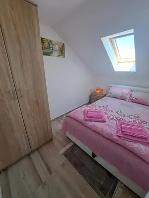 a bedroom with a pink bed and a wooden cabinet at Relja in Soko Banja