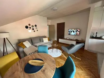 a living room with a wooden table and blue chairs at MD apartman Vranje FREE PARKING in Vranje