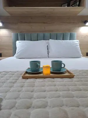 a tray with two cups and a candle on a bed at Lux apartmani Dunja Kopaonik Čardaci - GREEN in Kopaonik