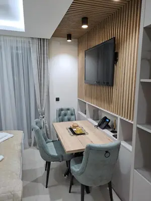 a room with a table and chairs and a television at Lux apartmani Dunja Kopaonik Čardaci - GREEN in Kopaonik