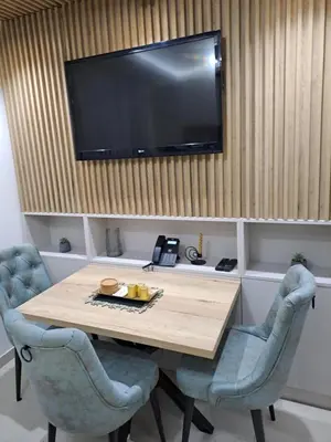 a dining room table with two chairs and a television on the wall at Lux apartmani Dunja Kopaonik Čardaci - GREEN in Kopaonik