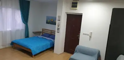 a bedroom with a blue bed and a chair at City center apartment 3 in Niš