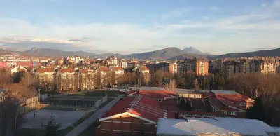 a view of a city with buildings and mountains at City center apartment 3 in Niš