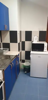 a small kitchen with blue cabinets and a white refrigerator at City center apartment 3 in Niš