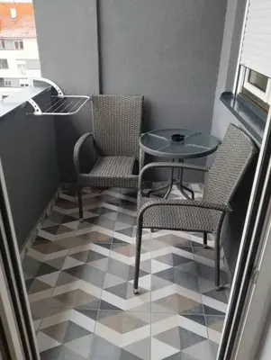 a small balcony with a table and chairs on a tiled floor at Welcome Apartments in Niš