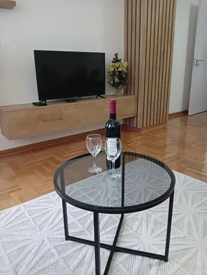 a glass table with a bottle of wine and two glasses at Welcome Apartments in Niš