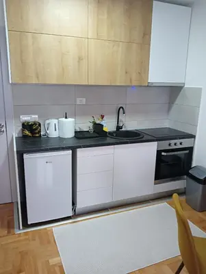 a kitchen with white cabinets and a sink at Welcome Apartments in Niš