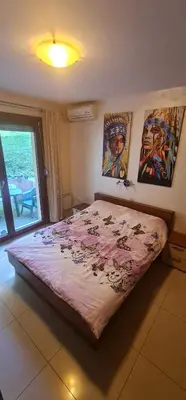 a large bed in a room with paintings on the wall at Apartman Pikolo VB in Vrnjačka Banja