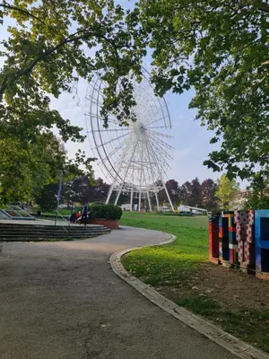 a large ferris wheel in a park with a tree at Apartman Pikolo VB in Vrnjačka Banja
