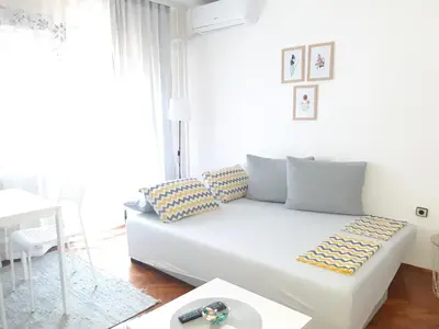 a white living room with a white couch in front of a window at Apartment Ljiljan 2 Niš in Niš