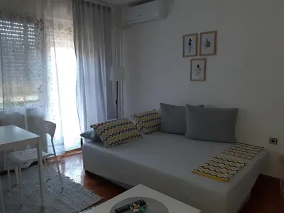 a living room with a white couch and a window at Apartment Ljiljan 2 Niš in Niš