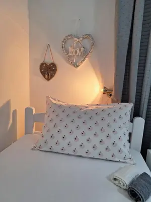 a bed with a pillow and a heart on the wall at Apartment Ljiljan 2 Niš in Niš