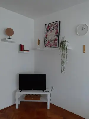 a white living room with a tv on a table at Apartment Ljiljan 2 Niš in Niš