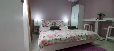 a bedroom with a large bed with pink flowers at KOSA APARTMAN in Vrnjačka Banja