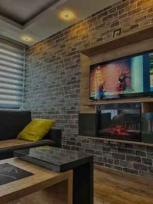 a living room with a tv on a brick wall at Apartman LED-Treska in Kopaonik