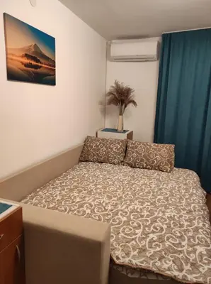 a small bedroom with a bed with a box at AVIS Apartment in Niš