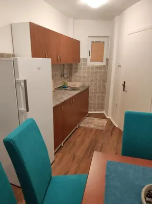 a kitchen with wooden cabinets and blue chairs at AVIS Apartment in Niš