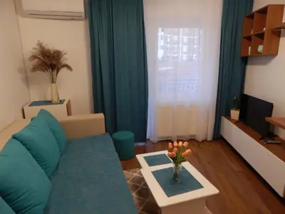 a living room with a blue couch and a table at AVIS Apartment in Niš
