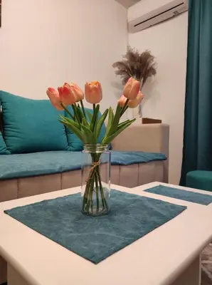 a vase of orange flowers sitting on a table at AVIS Apartment in Niš