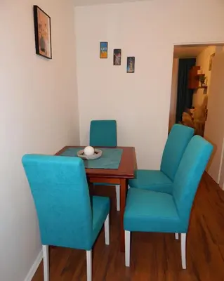 a dining room table with blue chairs and a bowl on it at AVIS Apartment in Niš