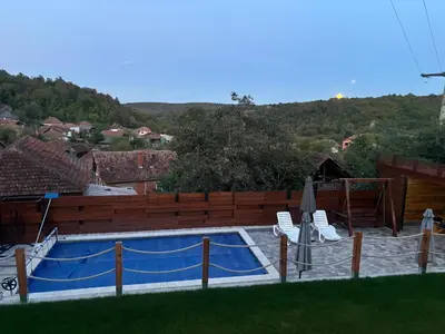 a swimming pool with two chairs and an umbrella at Rtanjska kućica in Boljevac