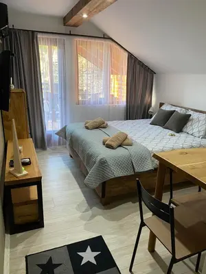 a bedroom with two beds and a table and a desk at Rtanjska kućica in Boljevac