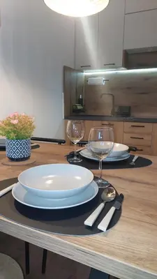 a table with two plates and wine glasses on it at Apartman 109 Vila Nikola in Kopaonik