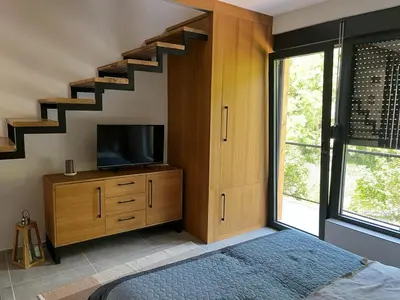 a bedroom with a bed and a tv and staircase at Domus in natura in Cerovak