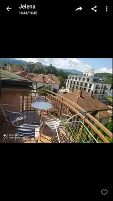 a balcony with chairs and a table and a building at Apartman Studio AGAPE in Vrnjačka Banja