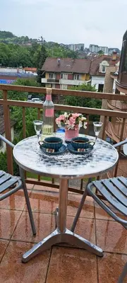 a table with two plates and a bottle on a balcony at Apartman Studio AGAPE in Vrnjačka Banja