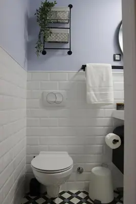 a white bathroom with a toilet and a towel rack at Vista Apartmani in Ribarska Banja