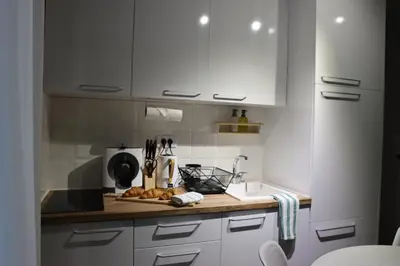 a kitchen with white cabinets and a wooden counter top at Vista Apartmani in Ribarska Banja